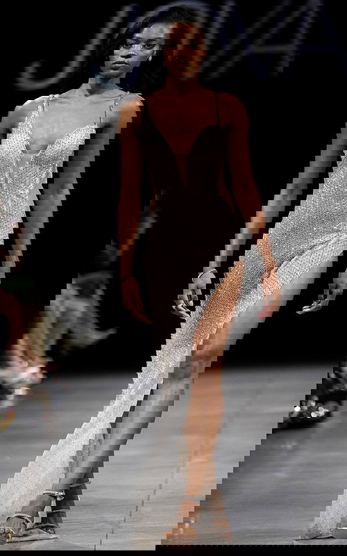 Model wearing Jovani S23022 beige gown with plunging neckline and high slit in front view