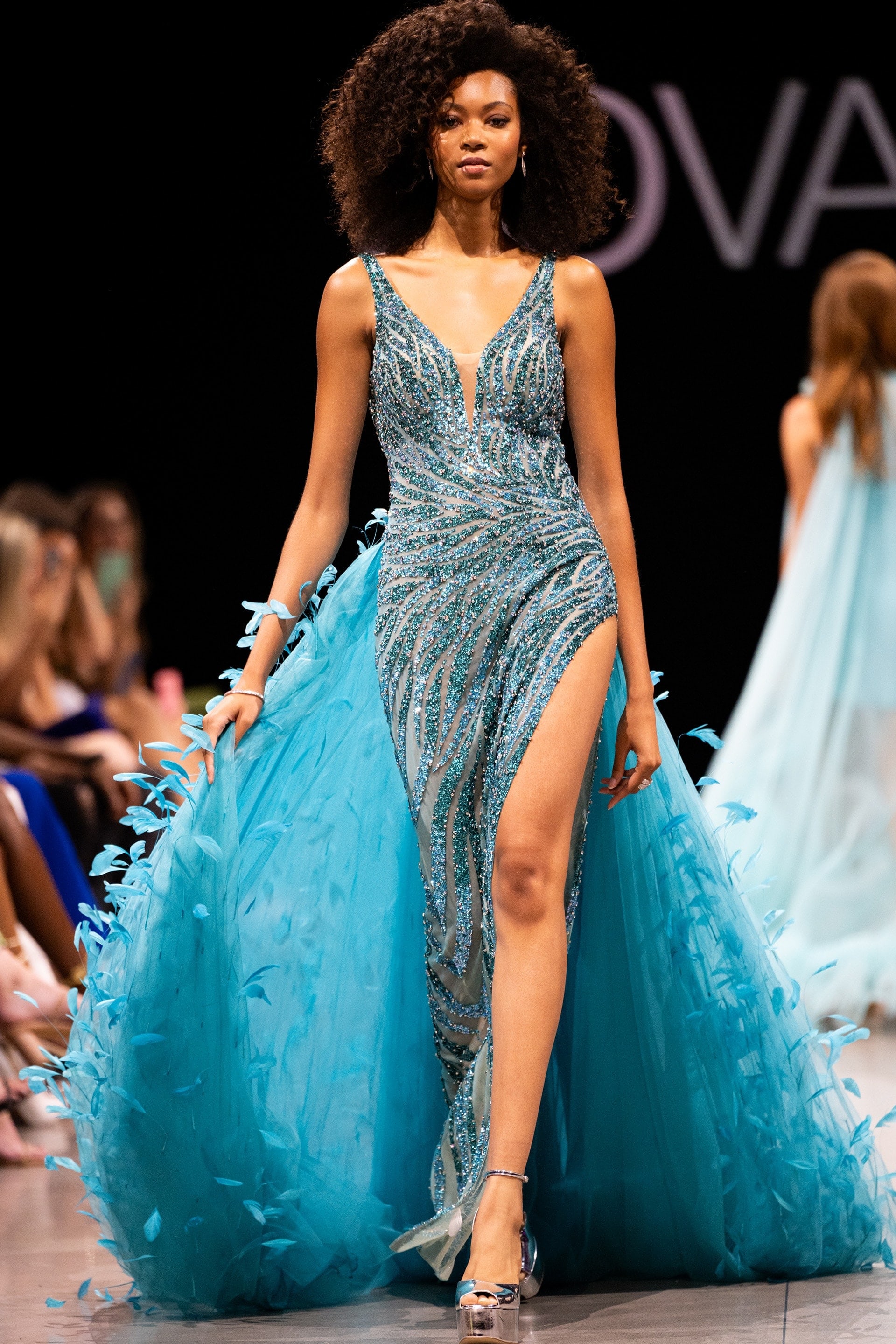 S23074.jpg Model wearing Jovani S23074 blue gown with feather-like back details.