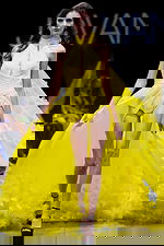 Model wearing Jovani S38104 yellow gown with halter neckline and flowing cape, front view.