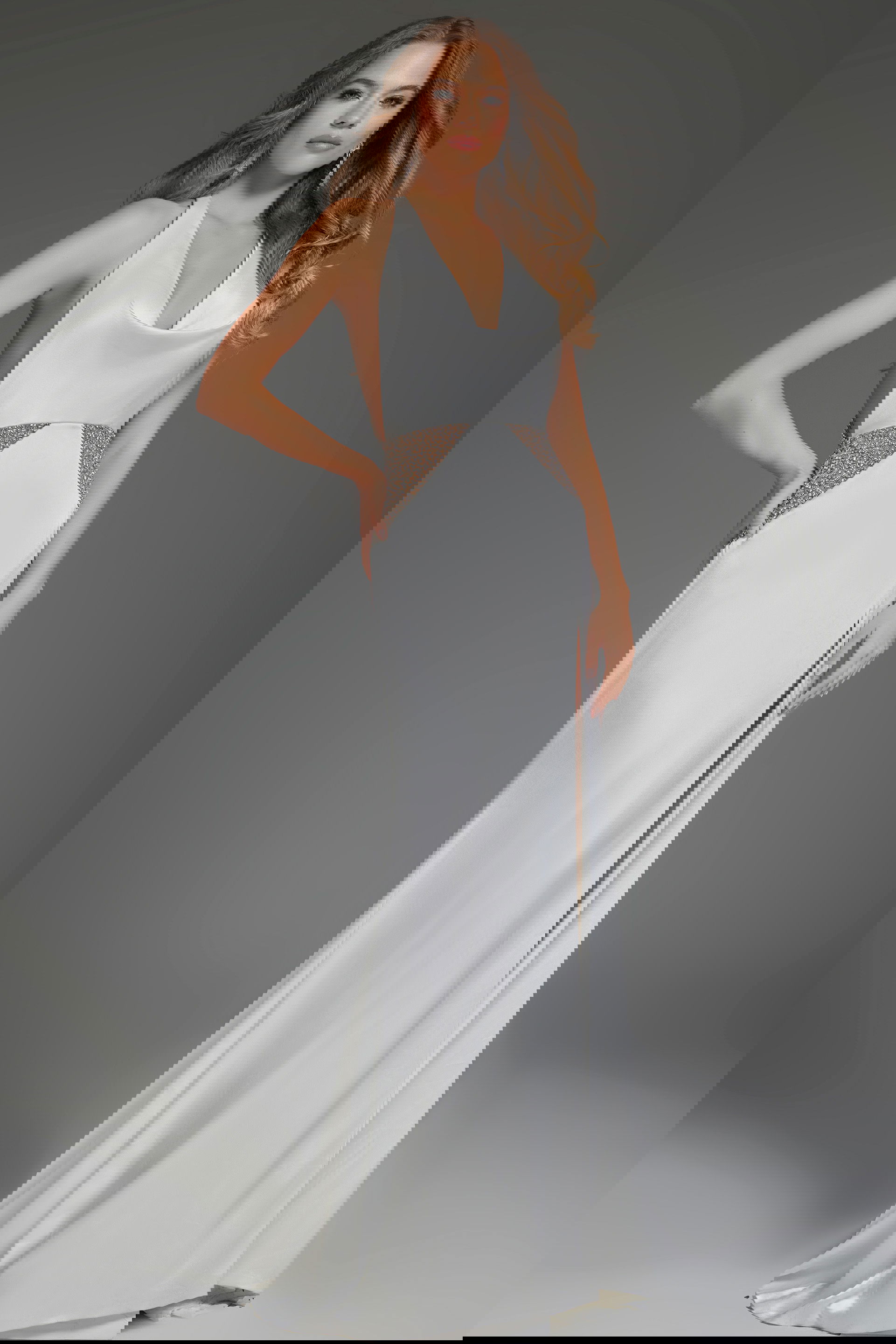 S43212-white-1 Model wearing S43212 white dress with a plunging neckline and beaded waist detail, front view.