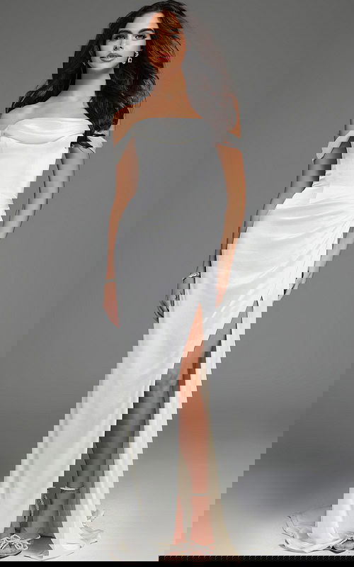 Model wearing Jovani 59780 white gown with an off-the-shoulder design and A-line silhouette, viewed from the back.