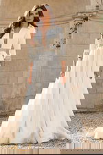 Front view of a long sleeve bridal gown with deep V neckline, flowing skirt, and crystal embellished waist.