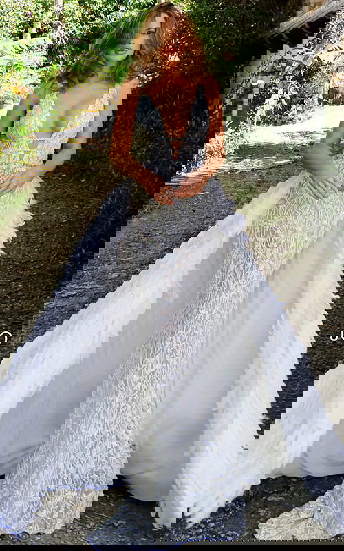 Model wearing Jovani S62942 white gown with mermaid silhouette and feather overlay.