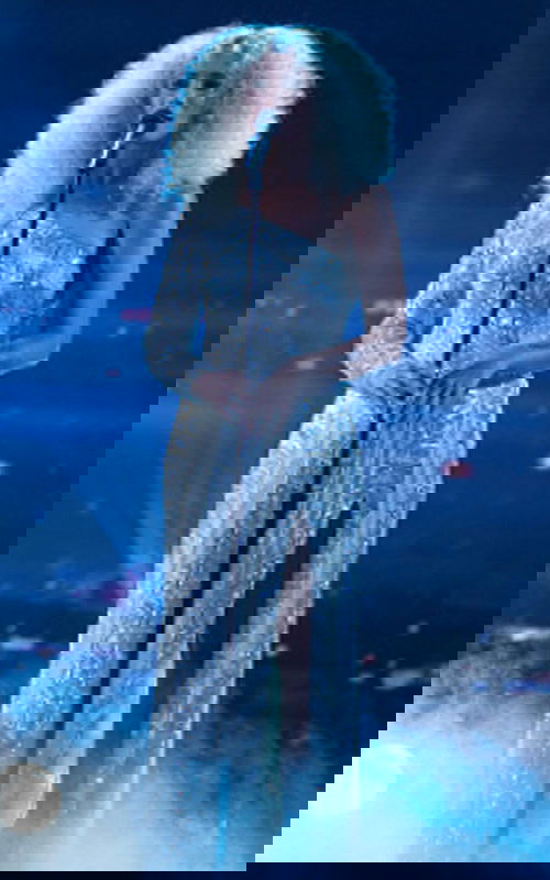 Model wearing Jovani 29341 nude gown with beaded detail, asymmetric neckline, and one long sleeve.