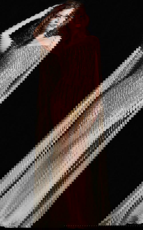 Model wearing Jovani 26324 gold gown with elegant beadwork and cape detail.