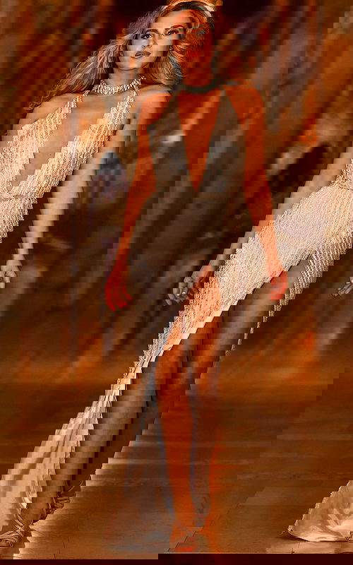 Model wearing Jovani S00937 silver gown with V-neckline and high slit.