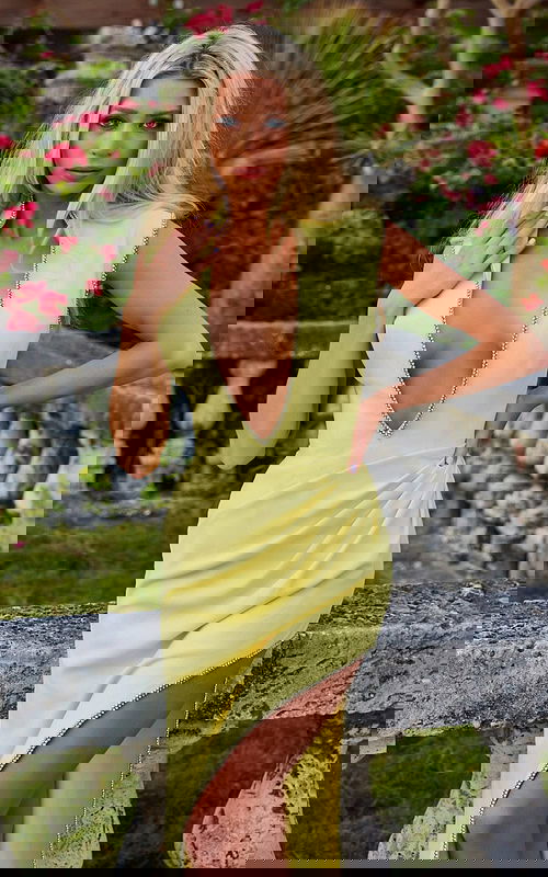 Model wearing Jovani s04667 yellow dress with deep V-neck and high slit, close-up view.